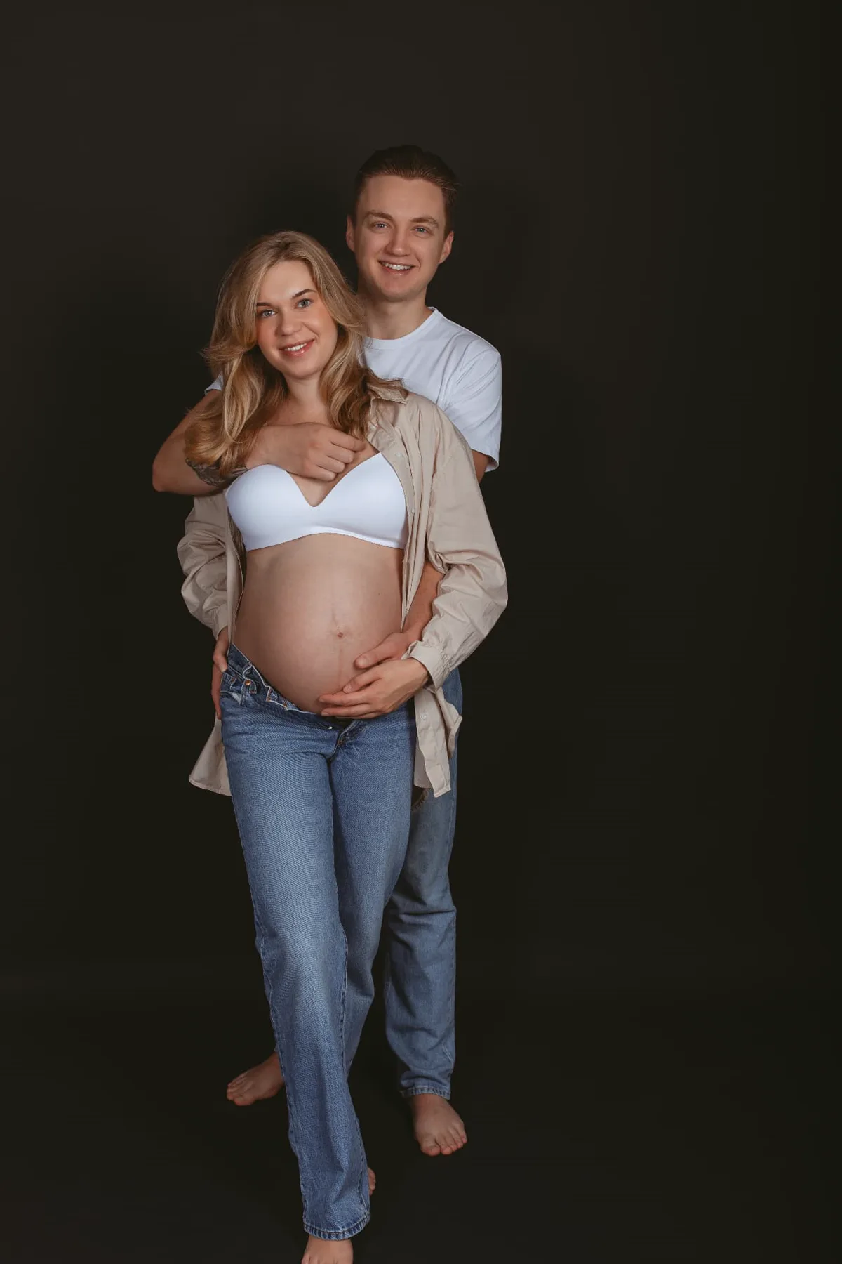 Zwanger stel in jeans tijdens een ontspannen studioshoot